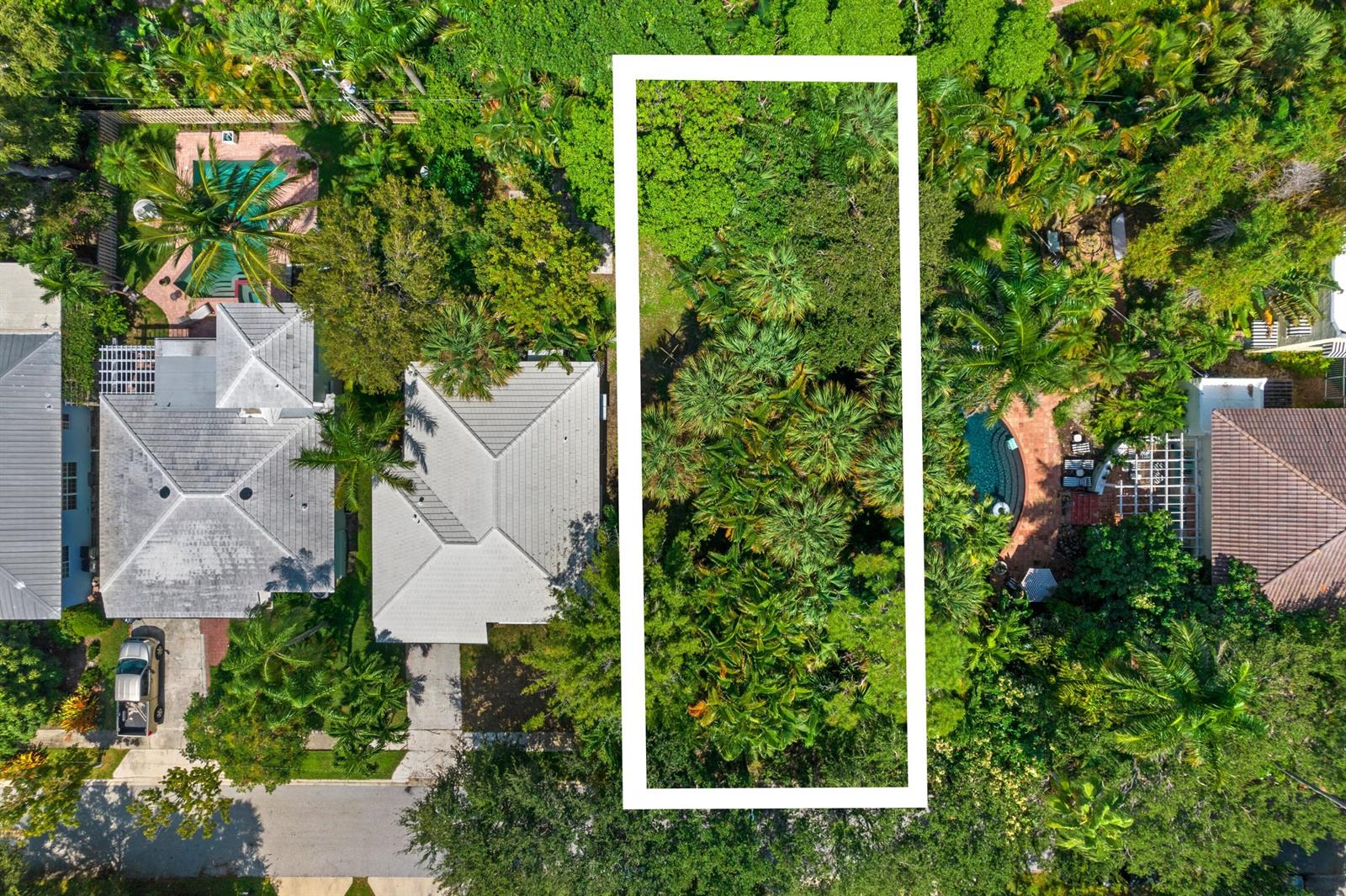 An aerial view shows a rectangular vacant lot surrounded by lush trees and residential houses — 00 17th Avenue S, FL 33460, FL