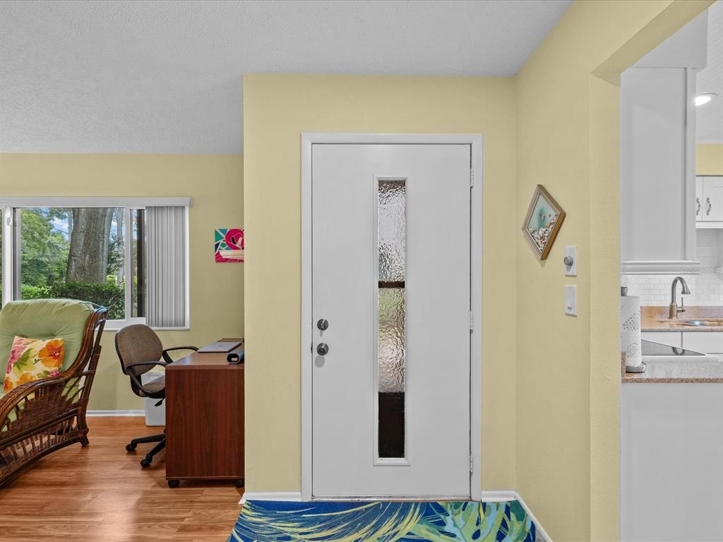 An entryway features a white front door with a vertical glass panel and light yellow walls — 13002 WEDGEWOOD WAY UNIT B, HUDSON, FL