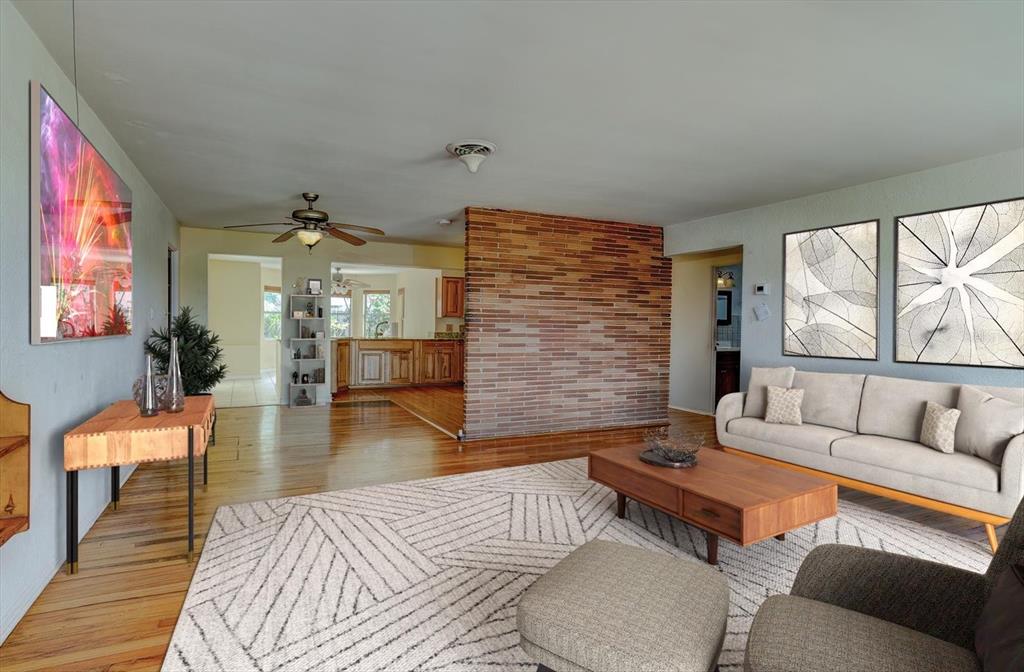 A living room features a brick accent wall, hardwood floors, and a large area rug — 3841 CARDINAL BOULEVARD, PORT ORANGE, FL