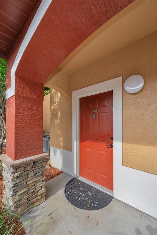 An exterior view of a front entrance with a red door and stone base pillar — 2199 CHIANTI PLACE UNIT 9-0925, PALM HARBOR, FL