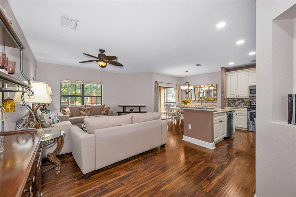 An open-concept living room and kitchen featuring hardwood floors, neutral walls, and recessed lighting — 2199 CHIANTI PLACE UNIT 9-0925, PALM HARBOR, FL