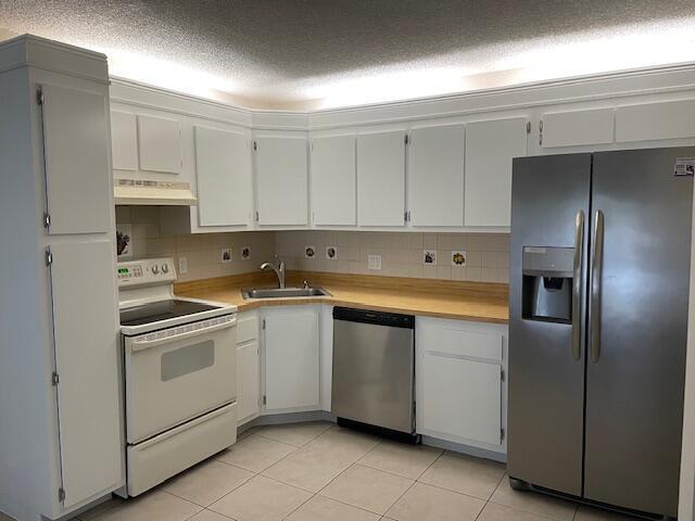 A kitchen features white cabinets, a light wood countertop, and stainless steel appliances — 204 Foxtail Drive # F2, FL 33415, FL