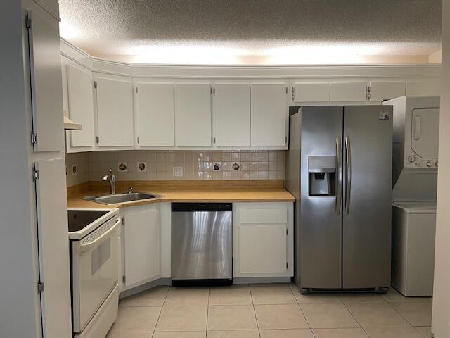 A kitchen features white cabinets, light countertops, stainless steel appliances, and a stacked laundry unit — 204 Foxtail Drive # F2, FL 33415, FL