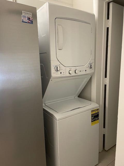 A white stacked washer and dryer unit stands next to a stainless steel refrigerator — 204 Foxtail Drive # F2, FL 33415, FL