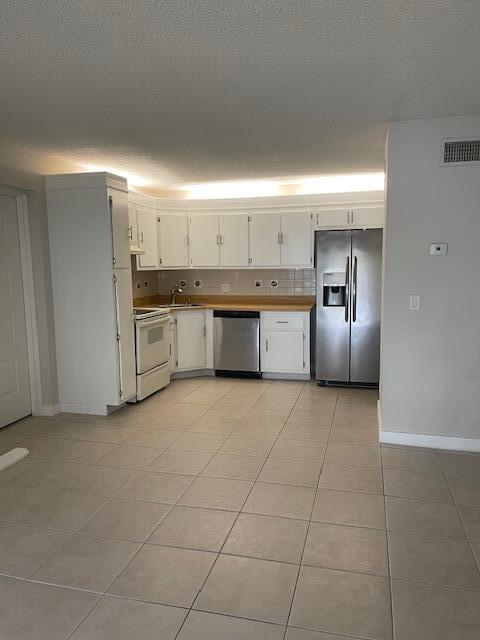 A kitchen with white cabinets, stainless steel appliances, and light-colored tile flooring — 204 Foxtail Drive # F2, FL 33415, FL