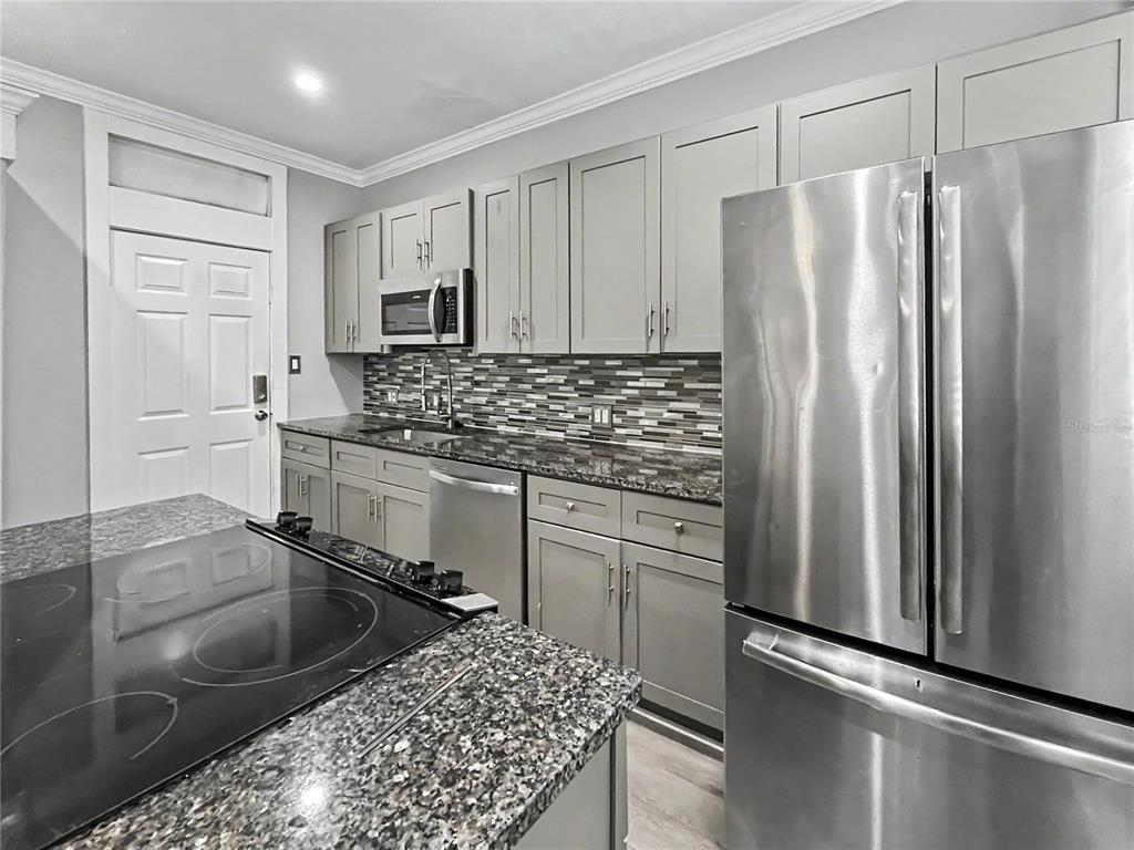 A kitchen features gray cabinets, stainless steel appliances, and a dark granite countertop island — 408 ARMADA ROAD S UNIT 2, VENICE, FL