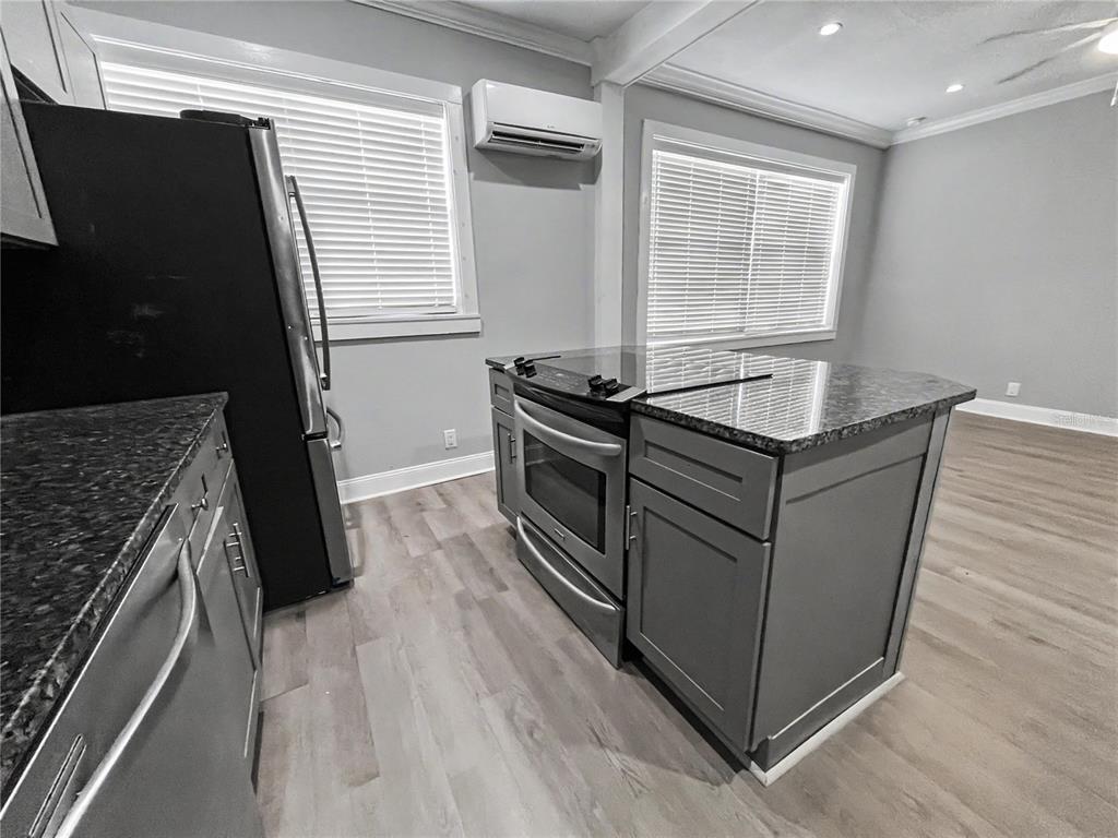 A kitchen features gray cabinets, dark granite countertops, stainless steel appliances, and light wood flooring — 408 ARMADA ROAD S UNIT 2, VENICE, FL
