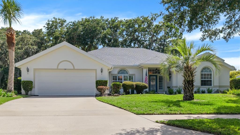 A single-story house with a two-car garage, a palm tree, and a manicured lawn — 52 SOUTHLAKE DRIVE, PALM COAST, FL