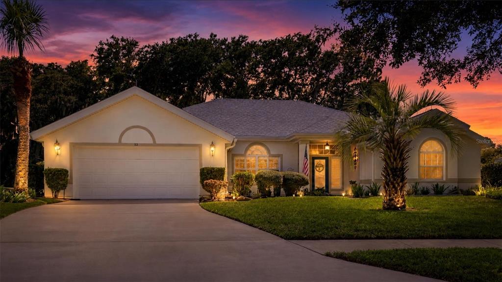 A single-story house with a two-car garage and a palm tree at sunset — 52 SOUTHLAKE DRIVE, PALM COAST, FL