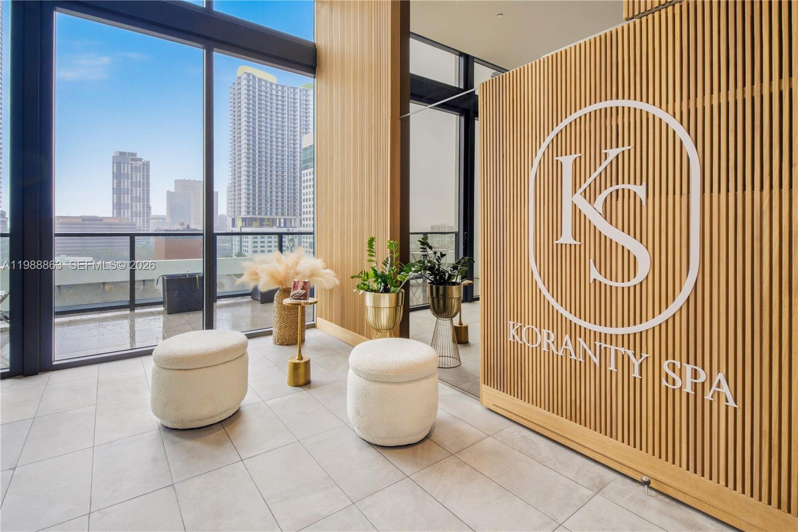 A modern spa reception area features a slatted wood wall, white ottomans, and city views — 239 SW 9th St # 802, Miami FL 33130, MIAMI, FL