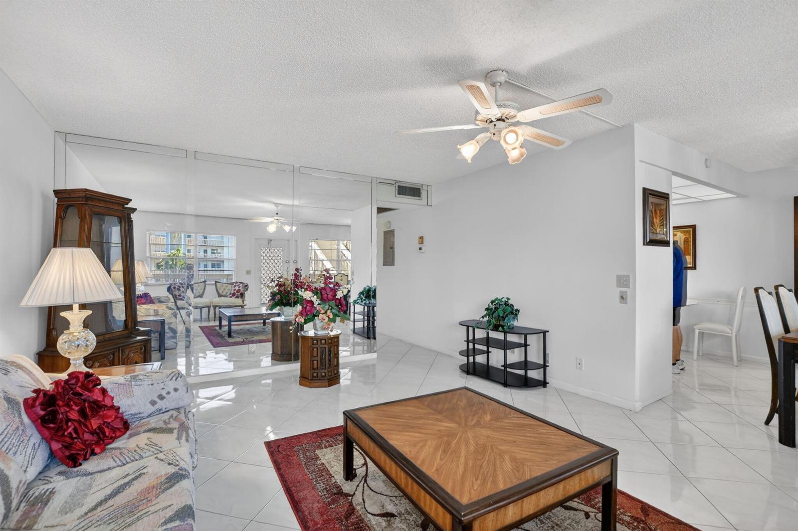 A living room with white tile floors, a mirrored wall, and a ceiling fan — 2035 Ainslie, Boca Raton FL 33434, BOCA RATON, FL