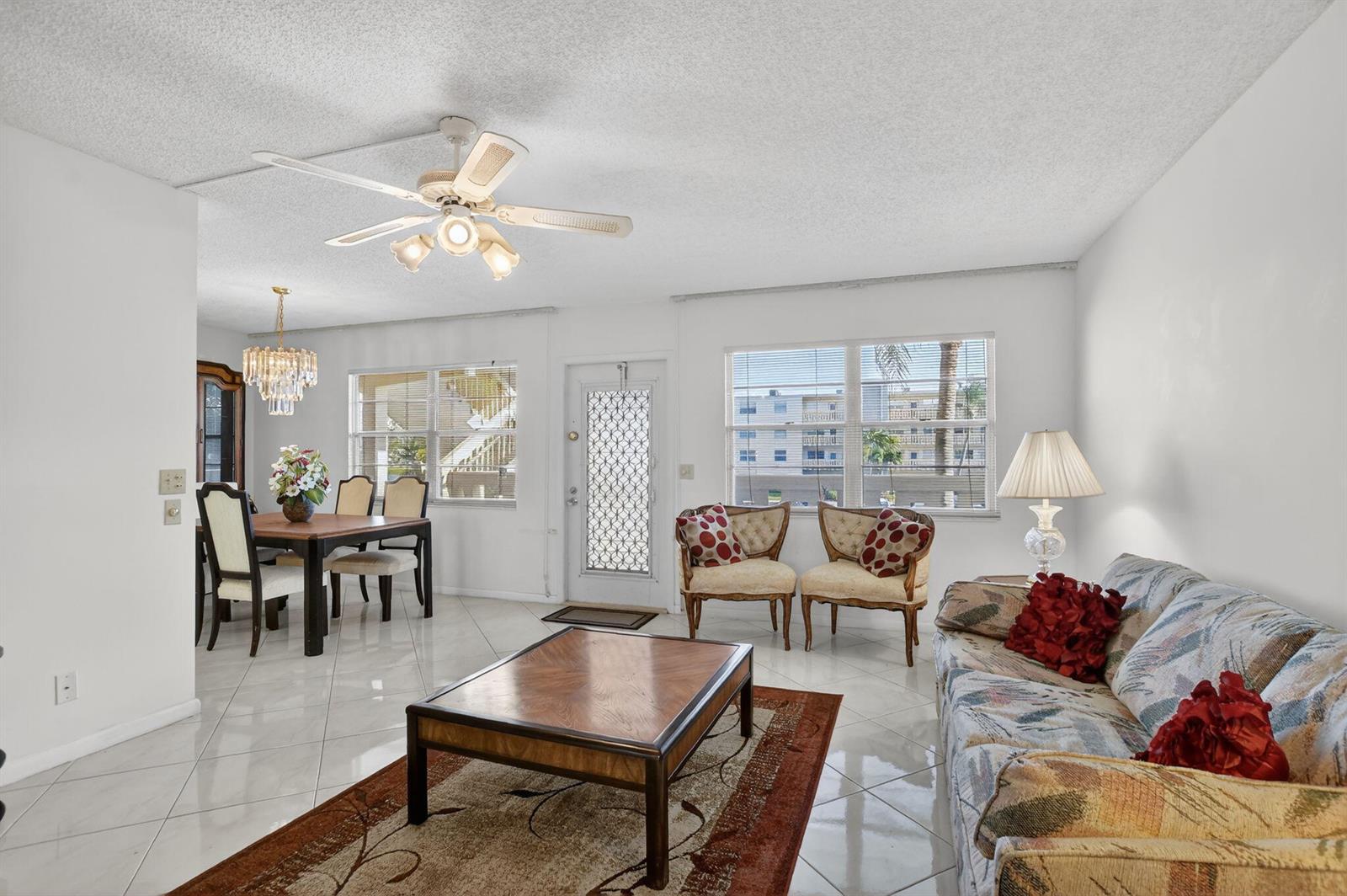 A living and dining room with white tile floors, a ceiling fan, and a front door — 2035 Ainslie, Boca Raton FL 33434, BOCA RATON, FL