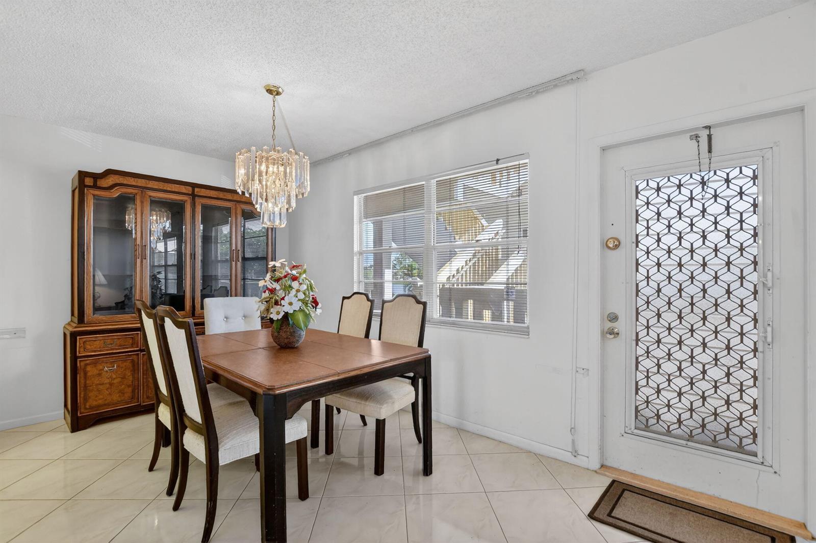 A dining room features a wooden table, chairs, a hutch, and a glass-paneled entry door — 2035 Ainslie, Boca Raton FL 33434, BOCA RATON, FL