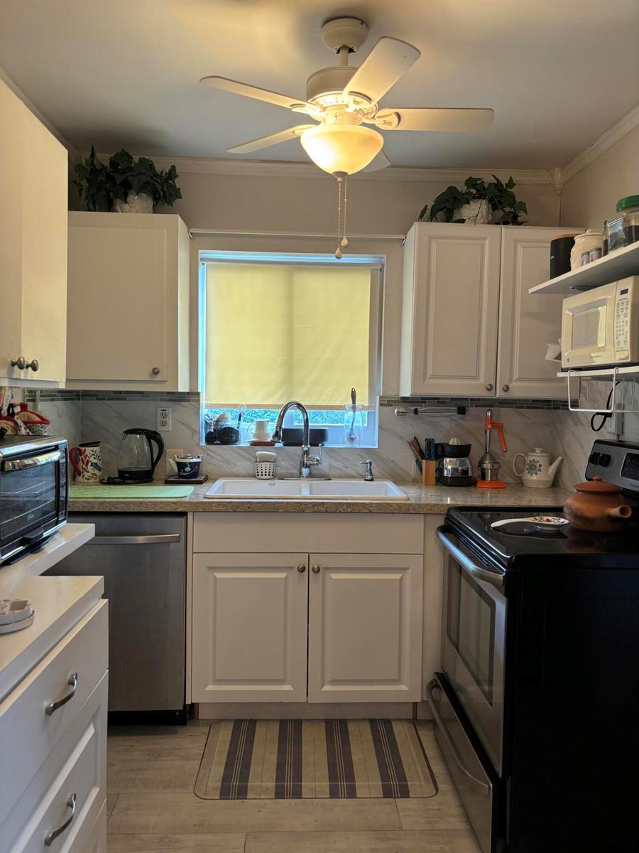 A kitchen features white cabinets, a double-basin sink, a ceiling fan, and black appliances — 326 Andover, West Palm Beach FL 33417, WEST PALM BEACH, FL