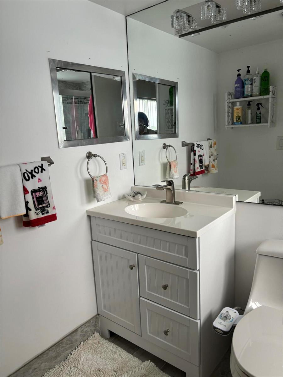 A bathroom features a white vanity with a sink, a large mirror, and a toilet — 326 Andover, West Palm Beach FL 33417, WEST PALM BEACH, FL