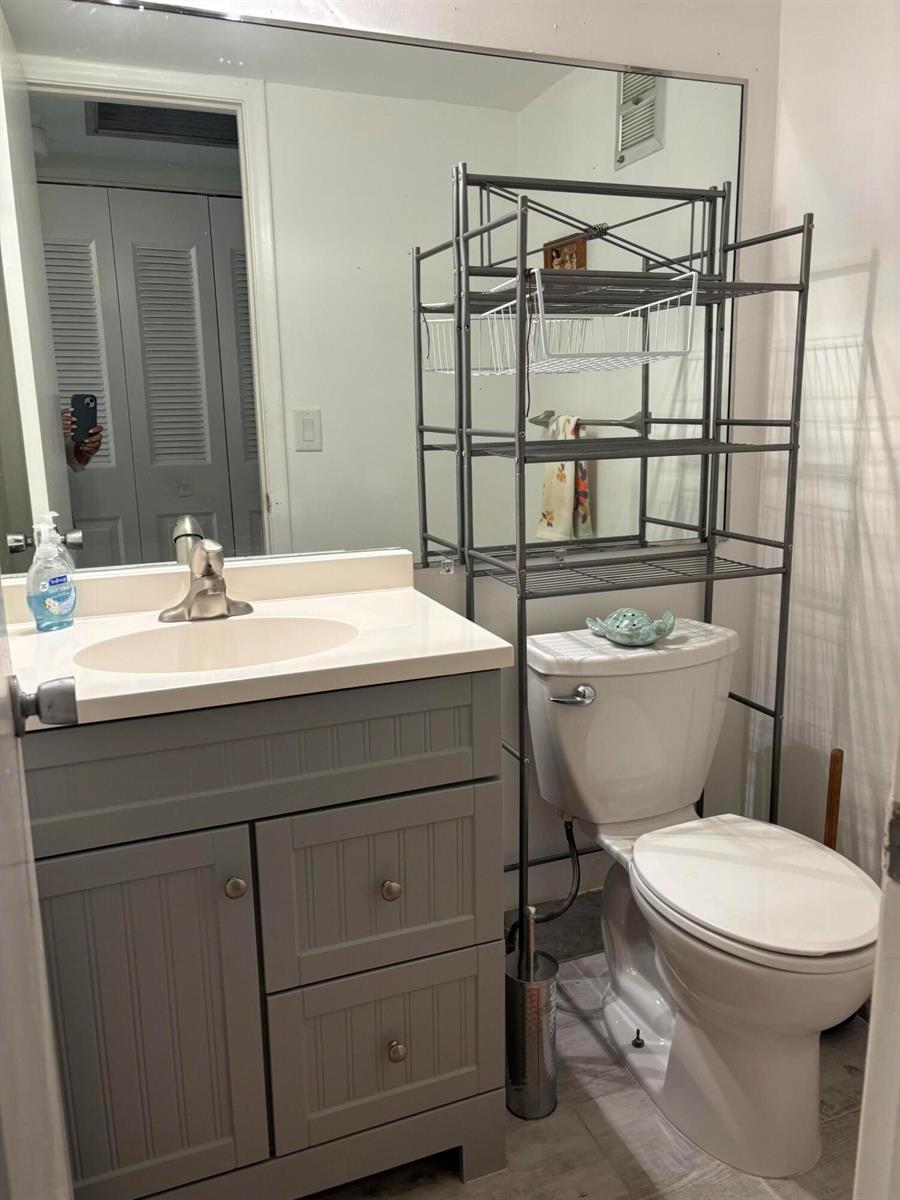 A bathroom features a grey vanity with a white countertop and an over-the-toilet storage rack — 326 Andover, West Palm Beach FL 33417, WEST PALM BEACH, FL