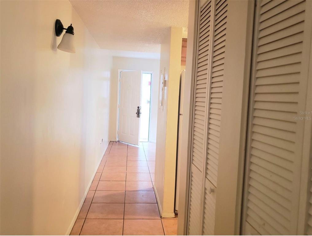 A hallway with tiled flooring leads to an open exterior door — 7100 WATERSIDE DRIVE, TAMPA, FL