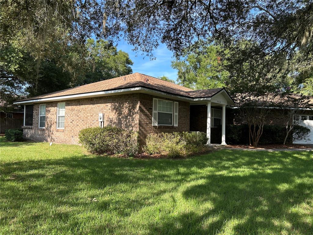 A single-story brick house with a hip roof and a covered front porch — 25459 SW 20TH PLACE, NEWBERRY, FL