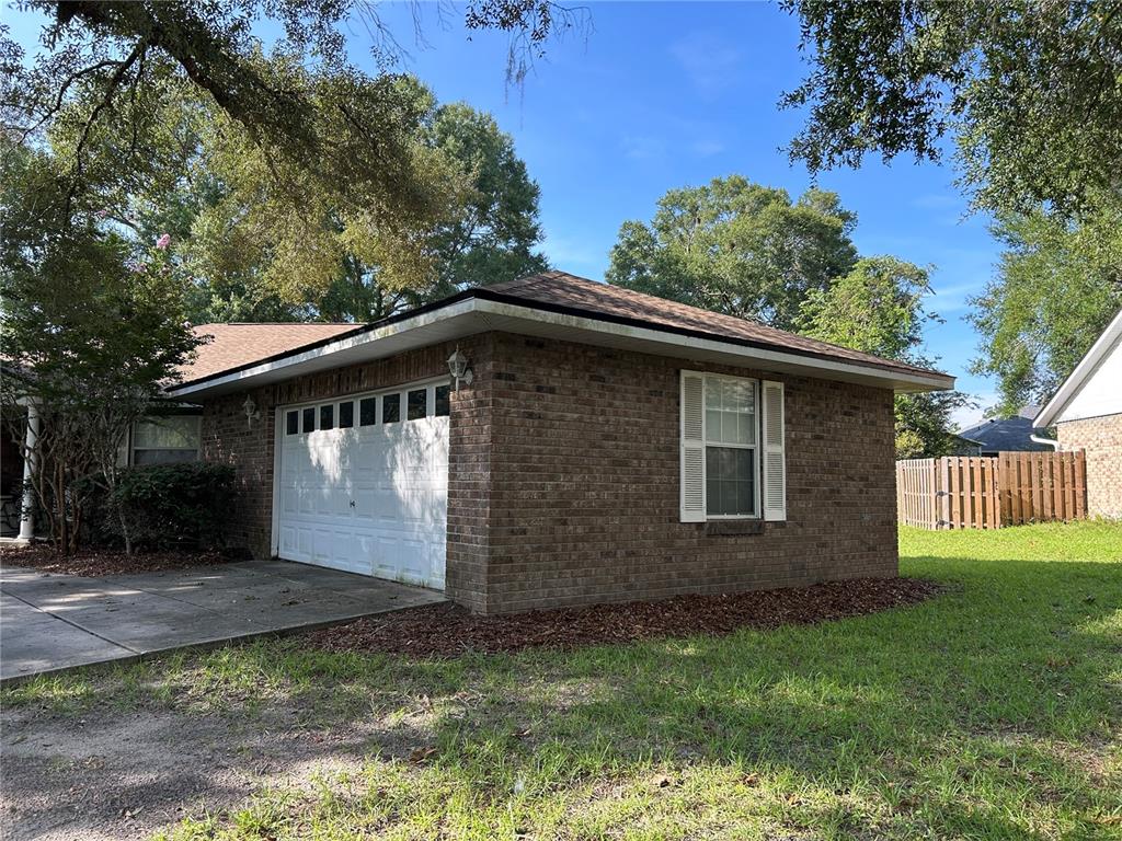 A brick garage with a white door and a single window sits on a lawn — 25459 SW 20TH PLACE, NEWBERRY, FL