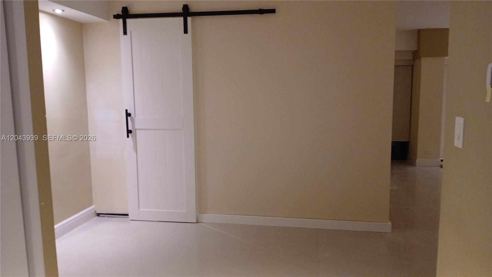 A white sliding barn door is mounted on a black track against a beige wall — 1800 NE 114th St # 508, Miami FL 33181, MIAMI, FL