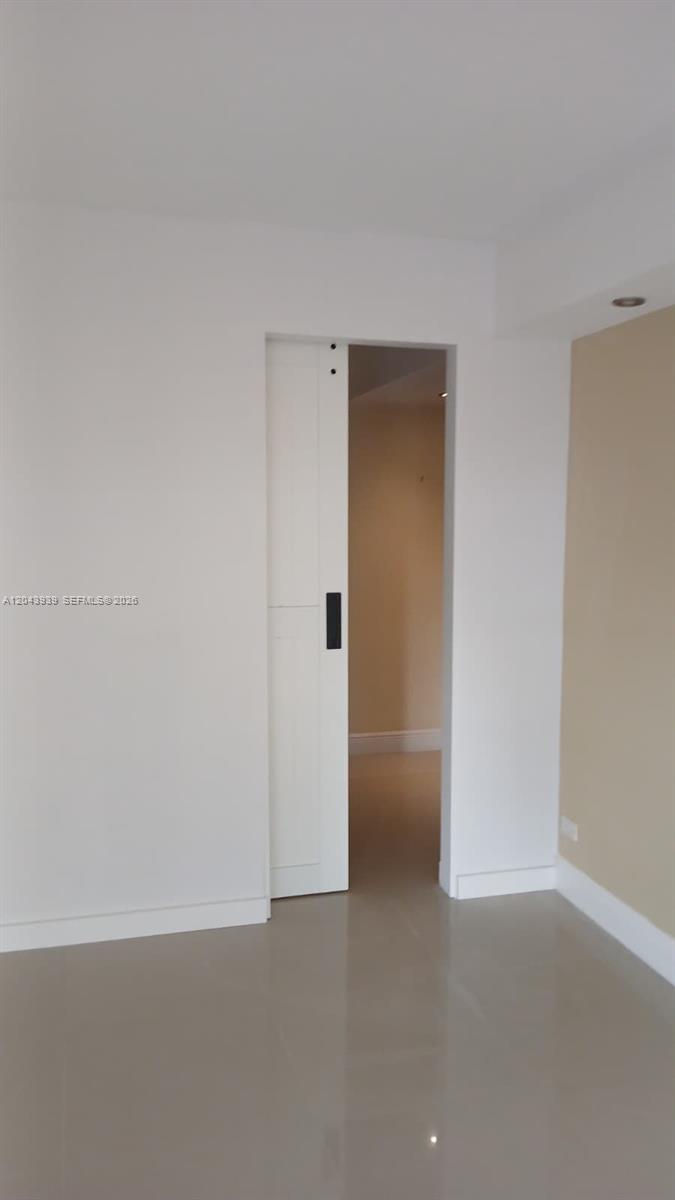 A white sliding barn door opens into a room with light-colored walls and flooring — 1800 NE 114th St # 508, Miami FL 33181, MIAMI, FL