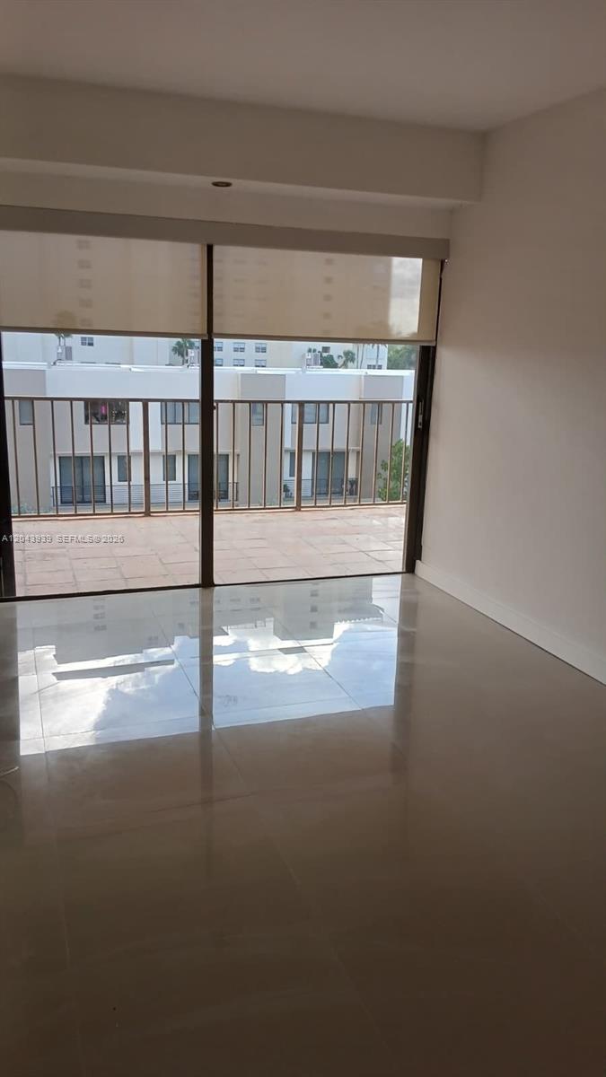 A room with glossy tile floors features a large sliding glass door leading to a balcony — 1800 NE 114th St # 508, Miami FL 33181, MIAMI, FL