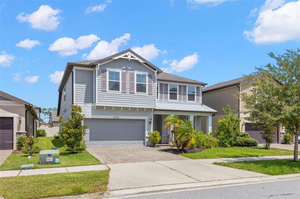 A two-story suburban house with light blue siding, a gray garage, and a paved driveway — 18935 BIRCHWOOD GROVES DRIVE, LUTZ, FL