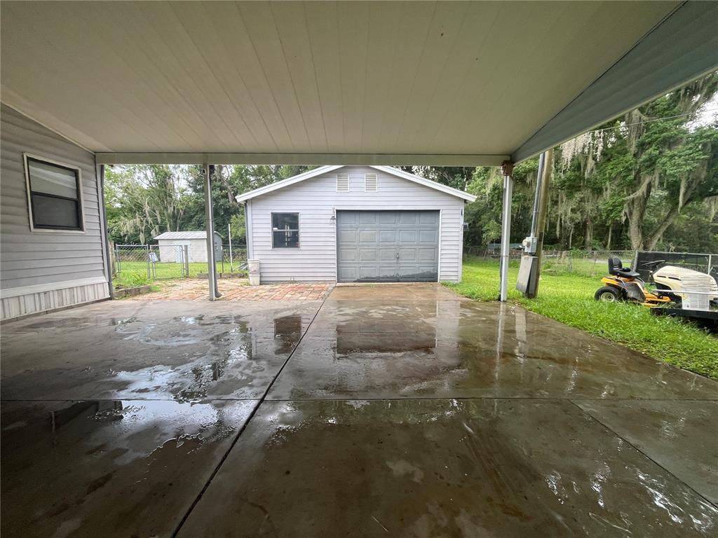 A concrete carport leads to a detached garage with a brick patio area — 4010 GLEN ROAD, LAKELAND, FL