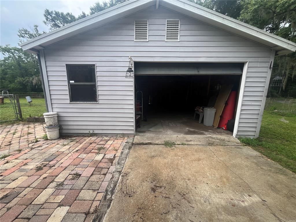A detached garage with gray siding, a single open bay, and a brick patio — 4010 GLEN ROAD, LAKELAND, FL