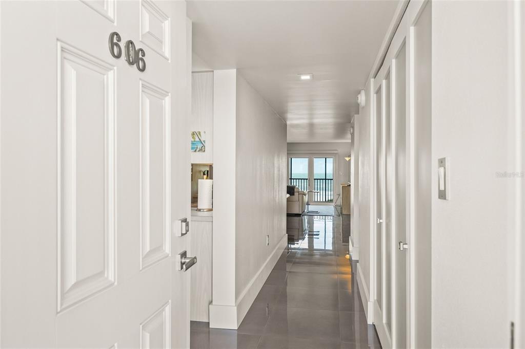 A view from an open doorway looking down a hallway toward a balcony with ocean views — 420 BEACH ROAD UNIT 606, SARASOTA, FL