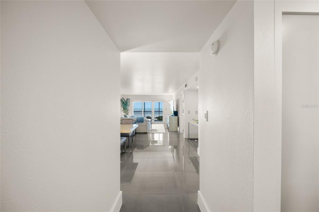 A bright hallway with gray tile flooring leads into a living area overlooking the ocean — 420 BEACH ROAD UNIT 606, SARASOTA, FL