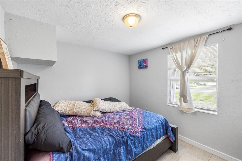 A bedroom features a bed with a blue patterned comforter, light walls, and a window — 6545 JACKSON STREET, NEW PORT RICHEY, FL