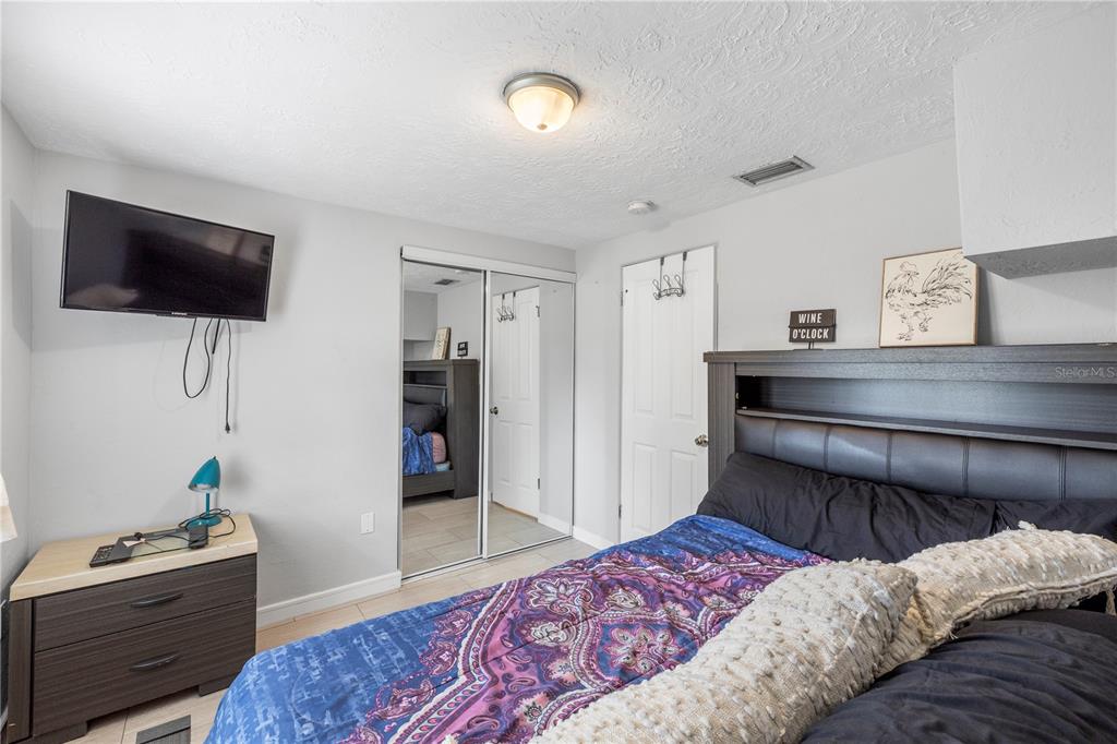 A bedroom features a bed with a dark headboard, a dresser, and mirrored closet doors — 6545 JACKSON STREET, NEW PORT RICHEY, FL