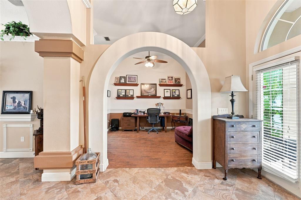 A home office is visible through a large arched opening in a tiled room — 18416 AUTUMN LAKE BOULEVARD, HUDSON, FL