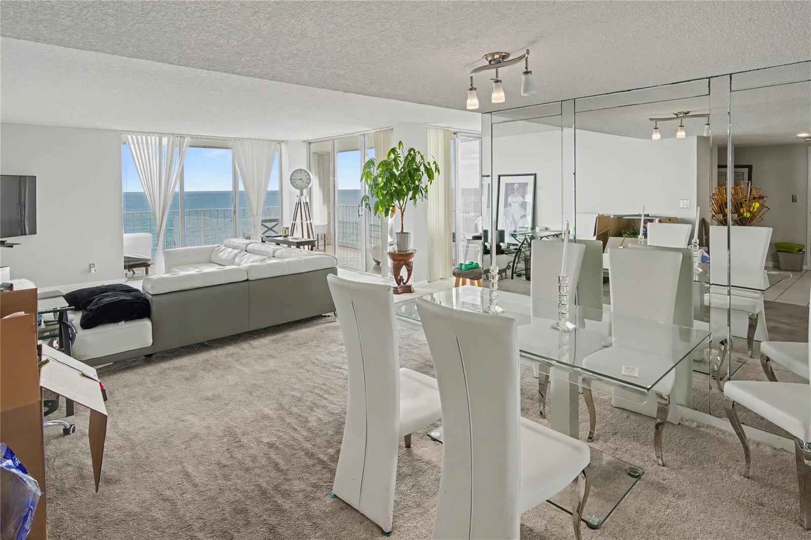 A living and dining area with white furniture, carpeted floors, and a view of the ocean — 1010 S Ocean Boulevard # 1601, Pompano Beach FL 33062, POMPANO BEACH, FL