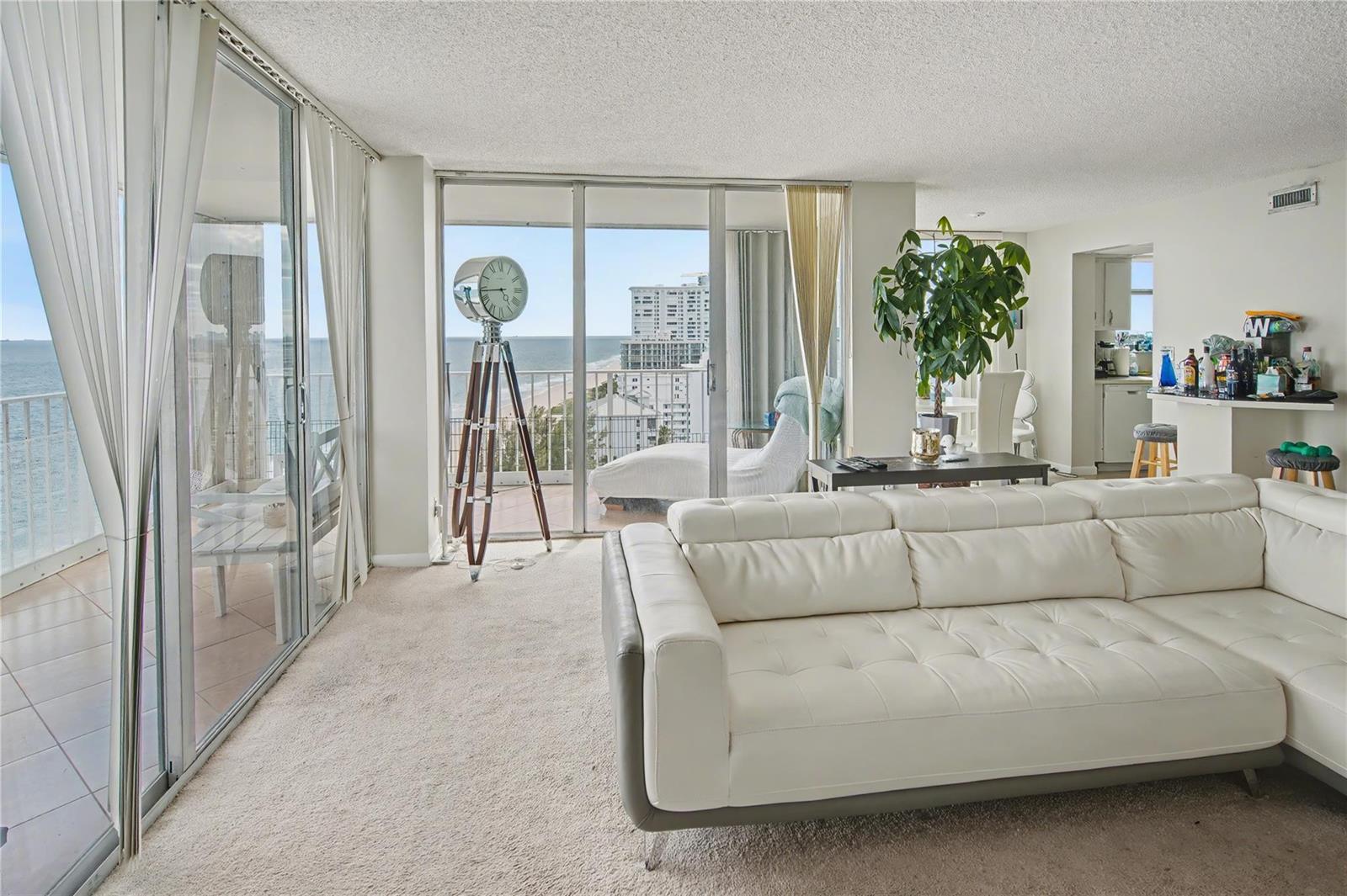 A living room with a white leather sectional, floor-to-ceiling windows, and a balcony overlooking the ocean — 1010 S Ocean Boulevard # 1601, Pompano Beach FL 33062, POMPANO BEACH, FL
