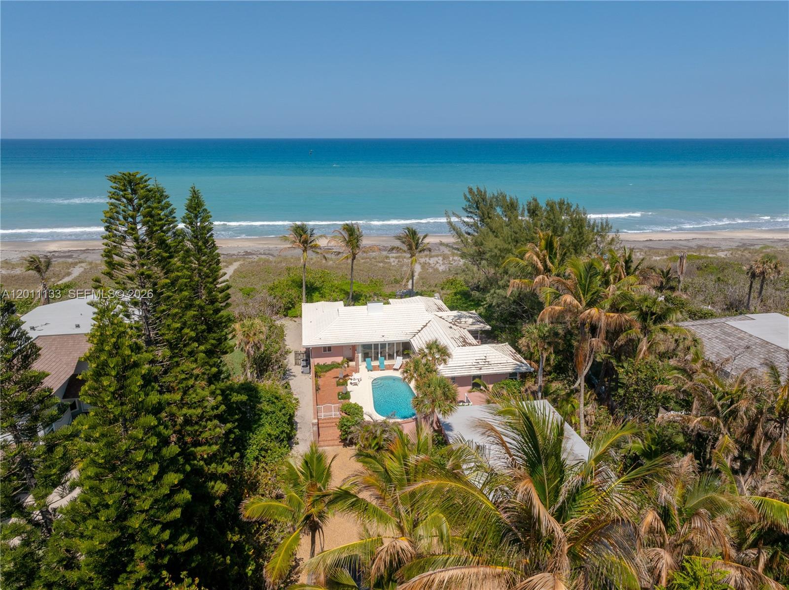 An aerial view shows a pink house with a swimming pool near the ocean — 55 N Beach Rd, Jupiter Island FL 33455, JUPITER ISLAND, FL