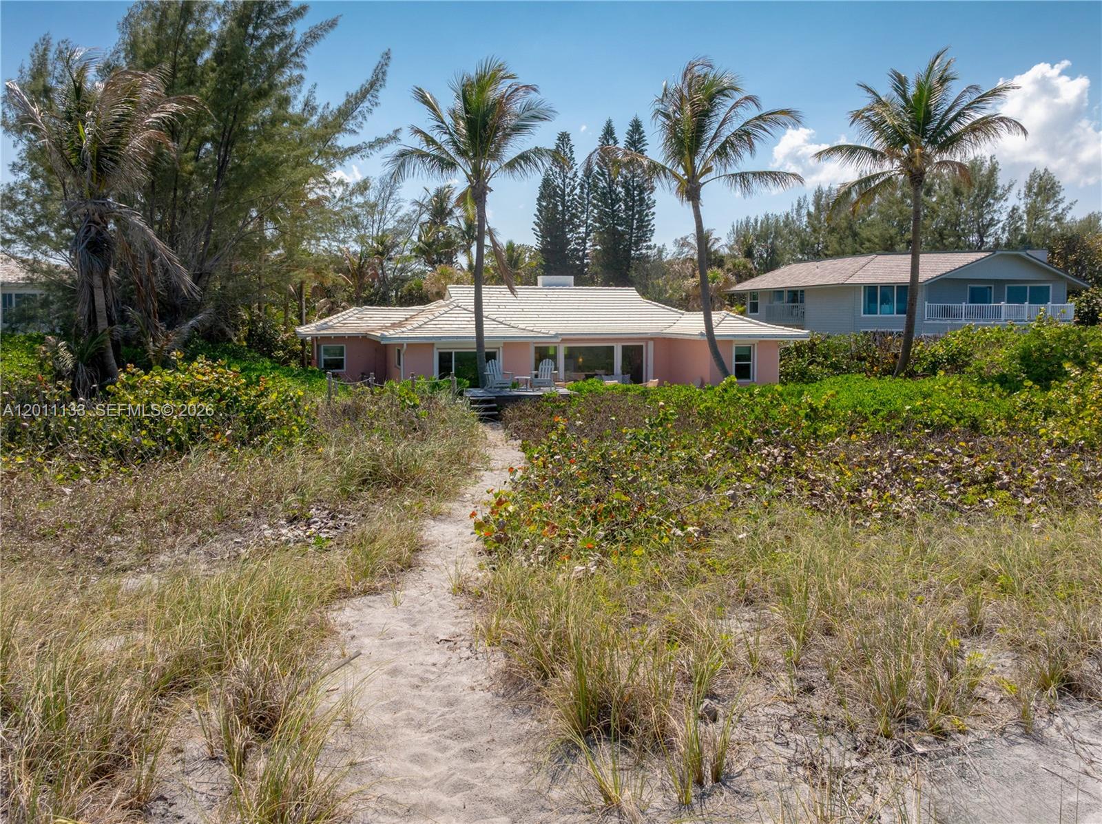A pink house with a tiled roof sits behind a sandy path and coastal vegetation — 55 N Beach Rd, Jupiter Island FL 33455, JUPITER ISLAND, FL