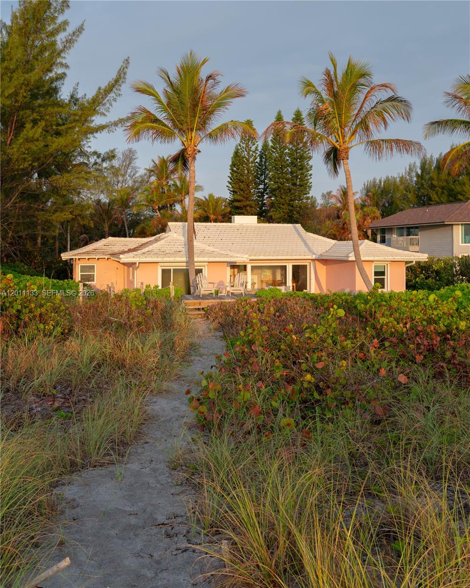 A pink, single-story house with a white roof is surrounded by palm trees and dunes — 55 N Beach Rd, Jupiter Island FL 33455, JUPITER ISLAND, FL