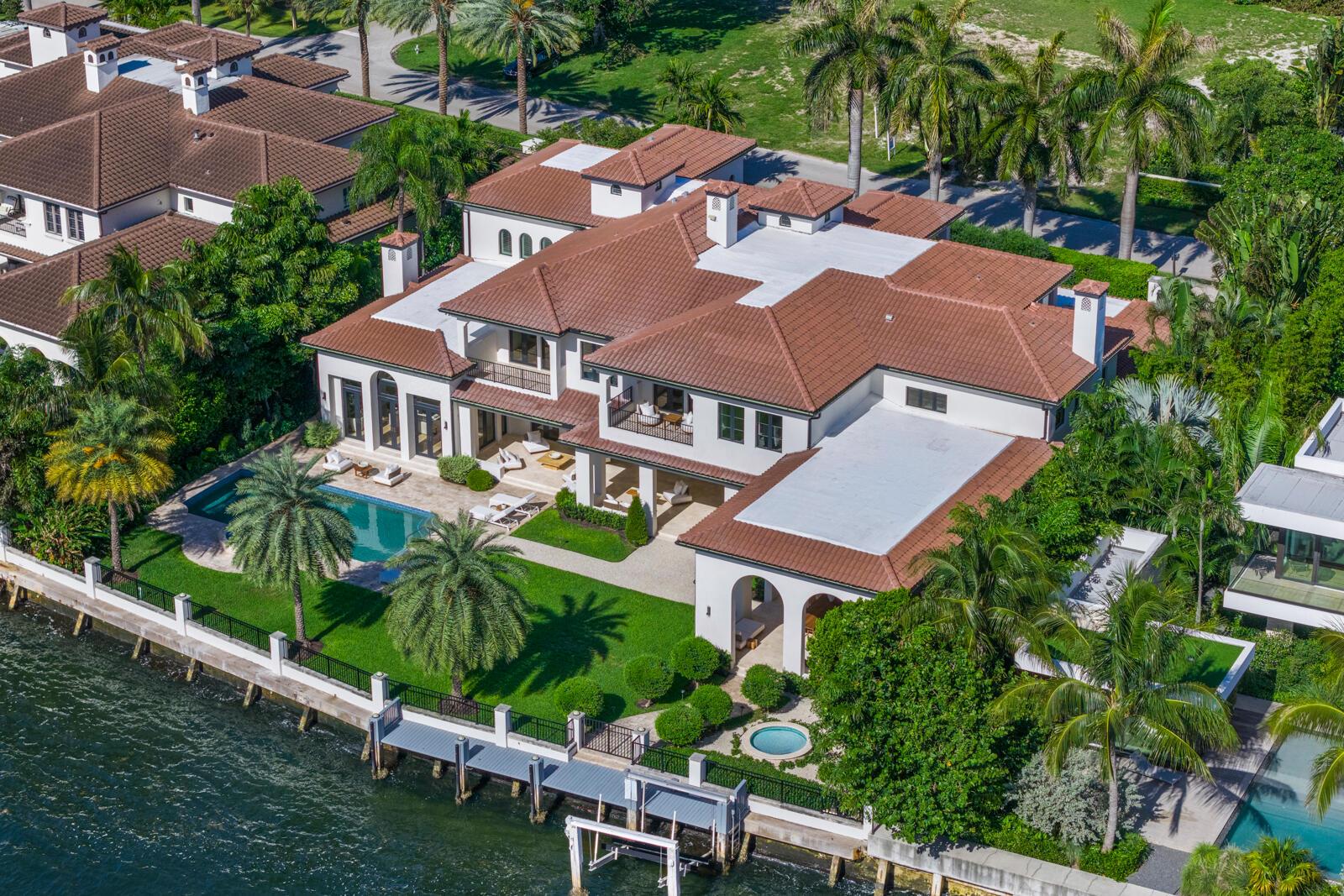 An aerial view of a waterfront mansion with a tiled roof, pool, and private dock — 1207 Spanish River Road, Boca Raton FL 33432, BOCA RATON, FL