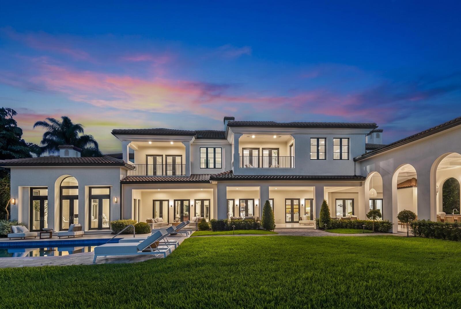 A two-story Mediterranean-style house with a pool, patio, and lawn at twilight — 1207 Spanish River Road, Boca Raton FL 33432, BOCA RATON, FL