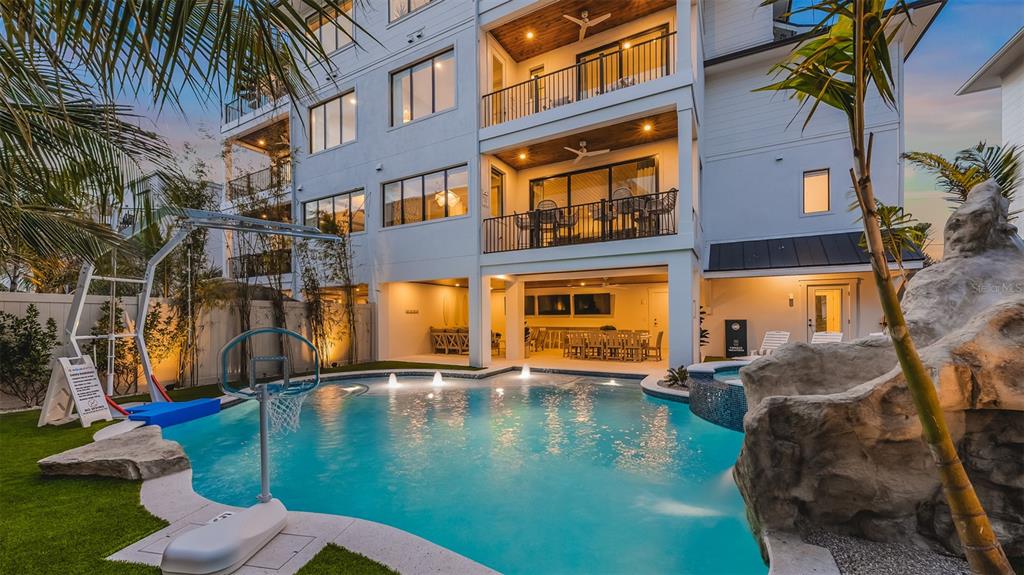 A multi-story house with balconies overlooks a swimming pool featuring a basketball hoop and rock — 1142 WINDSONG LANE UNIT A, SARASOTA, FL