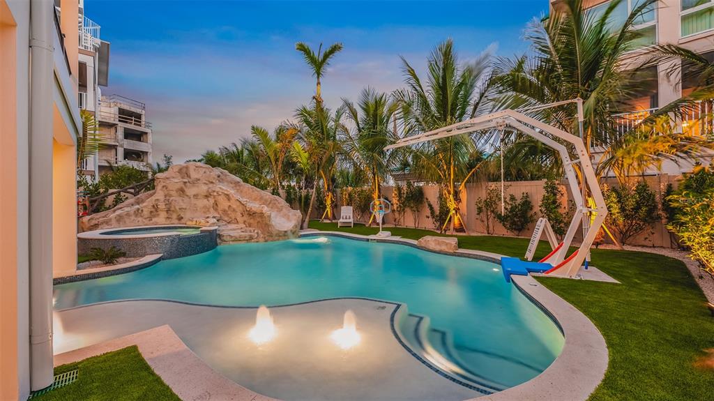 A backyard swimming pool with a rock slide, hot tub, fountains, and a basketball hoop — 1142 WINDSONG LANE UNIT A, SARASOTA, FL