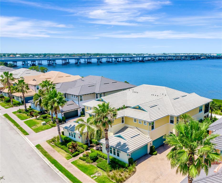 An aerial view of waterfront houses with palm trees and a large bridge nearby — 1264 RIVERSCAPE STREET UNIT B, BRADENTON, FL