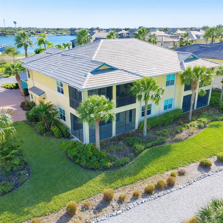 An aerial view of a two-story yellow building with screened balconies and a tiled roof — 1264 RIVERSCAPE STREET UNIT B, BRADENTON, FL