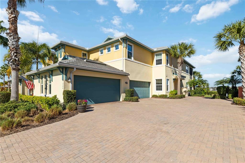A two-story yellow house with a paver driveway and two garage doors — 1264 RIVERSCAPE STREET UNIT B, BRADENTON, FL