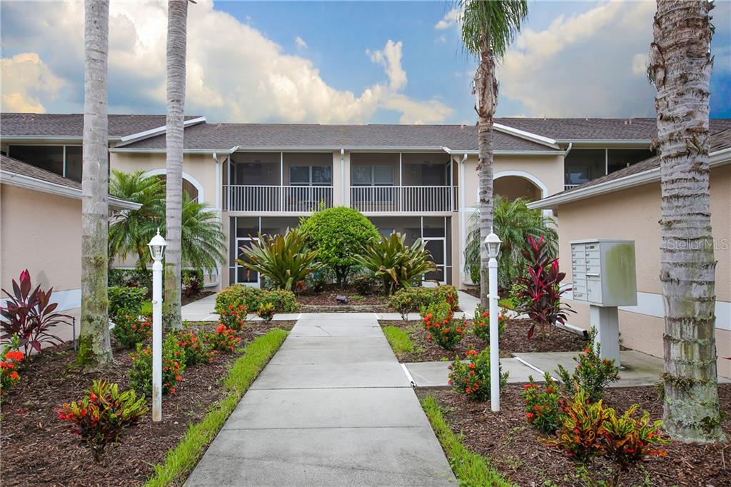 A concrete walkway leads to the entrance of a two-story apartment building with screened balconies — 5330 HYLAND HILLS AVENUE UNIT 2321, SARASOTA, FL