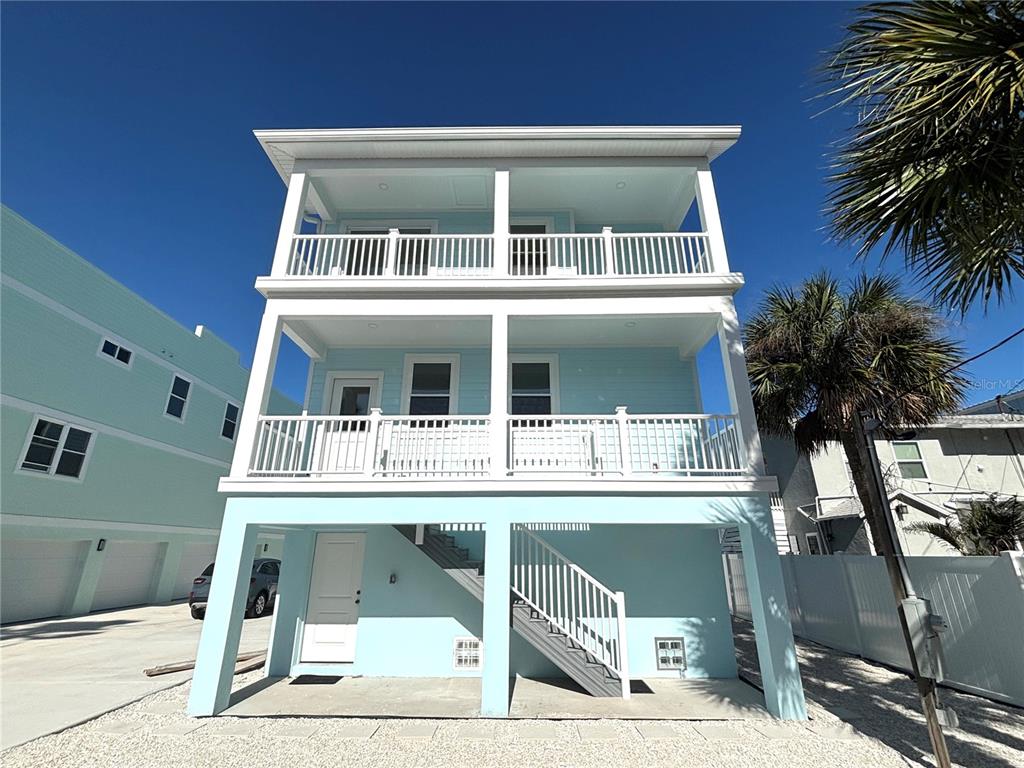 A three-story light blue house with two levels of balconies and an outdoor staircase — 711 GULF BOULEVARD, INDIAN ROCKS BEACH, FL