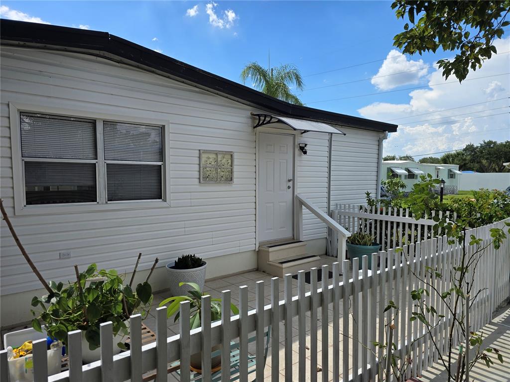 A white mobile home exterior features a small porch, a white picket fence, and windows — 5316 53RD AVENUE E UNIT A21, BRADENTON, FL