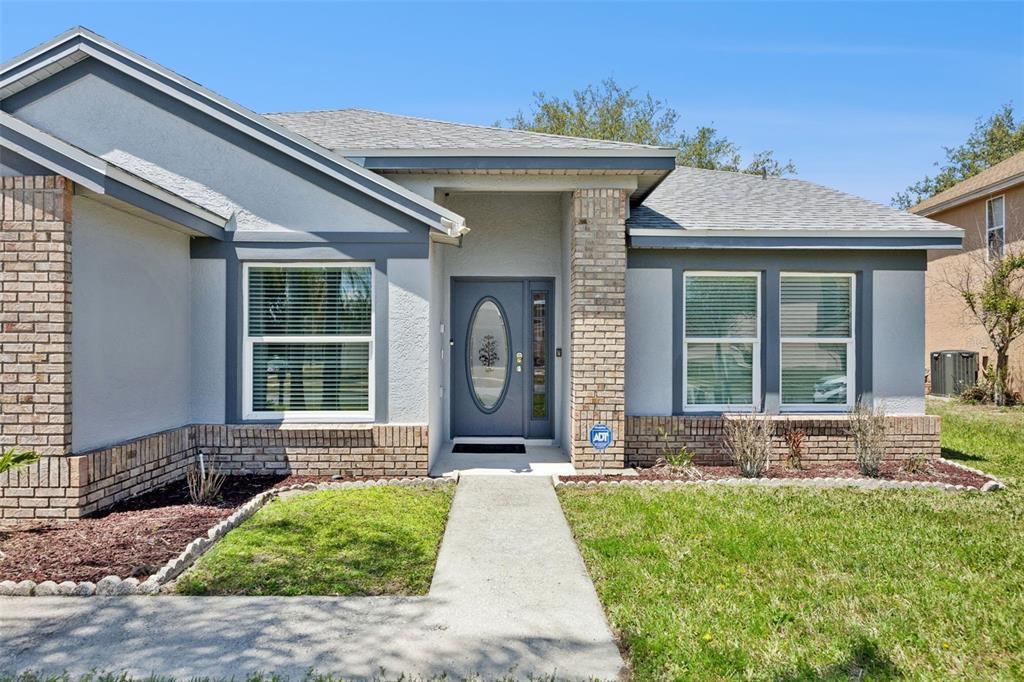 A single-story house with gray stucco, brick accents, and a front walkway under a clear sky — 2948 PEMBRIDGE STREET, KISSIMMEE, FL